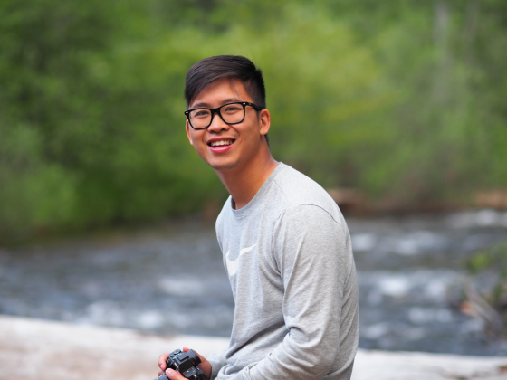 graduate student enjoys outdoor near a river with camera in hand